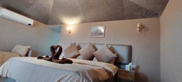 A bedroom with a bed, pillows, a wall-mounted light, and a picture.