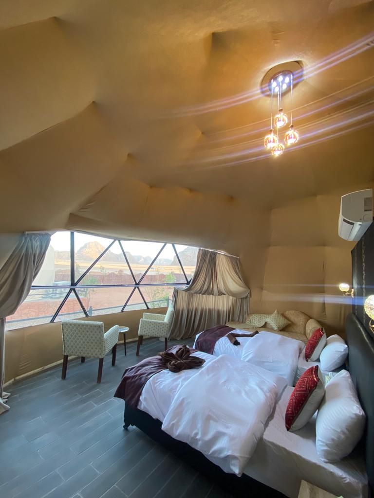 Een ruime slaapkamer met een groot bed, een stoel en uitzicht op de woestijn door een groot raam.