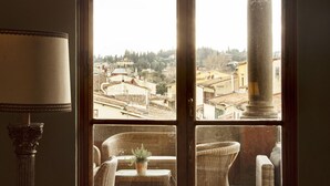 A room with a large window, wicker furniture, and a small table. - Hotel Palazzo Guadagni (Florence)