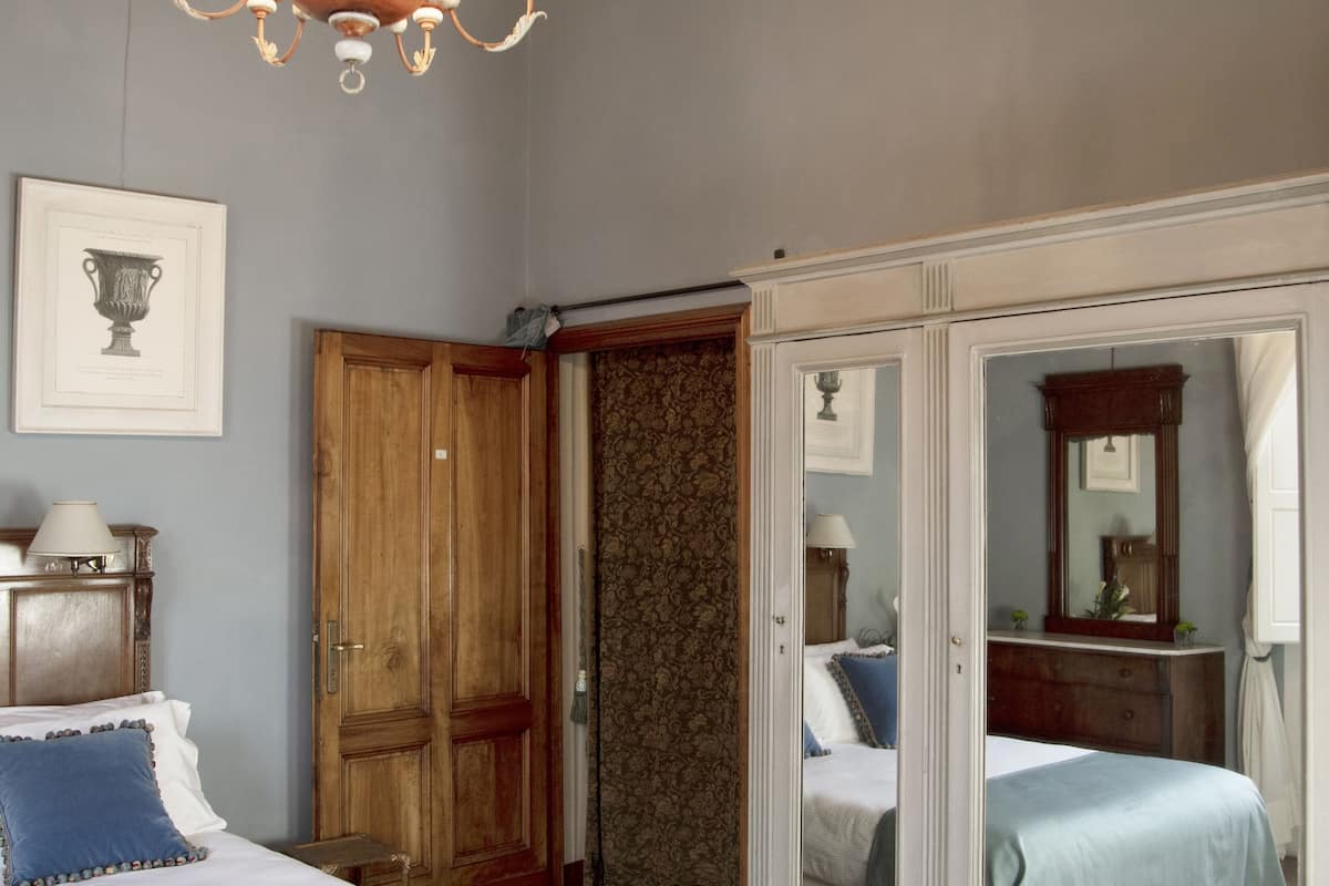 Une chambre à coucher avec un grand lit, une armoire, un miroir et un lustre.