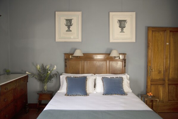 A bedroom with a wooden headboard, two bedside tables with lamps, a dresser, and a door.