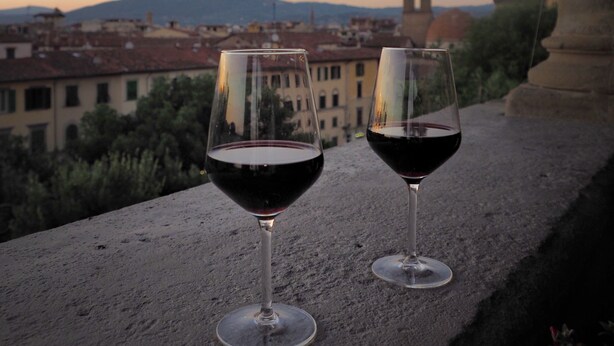 Two wine glasses on a balcony with a view of a tower and buildings in the background. - Hotel Palazzo Guadagni (Florence)