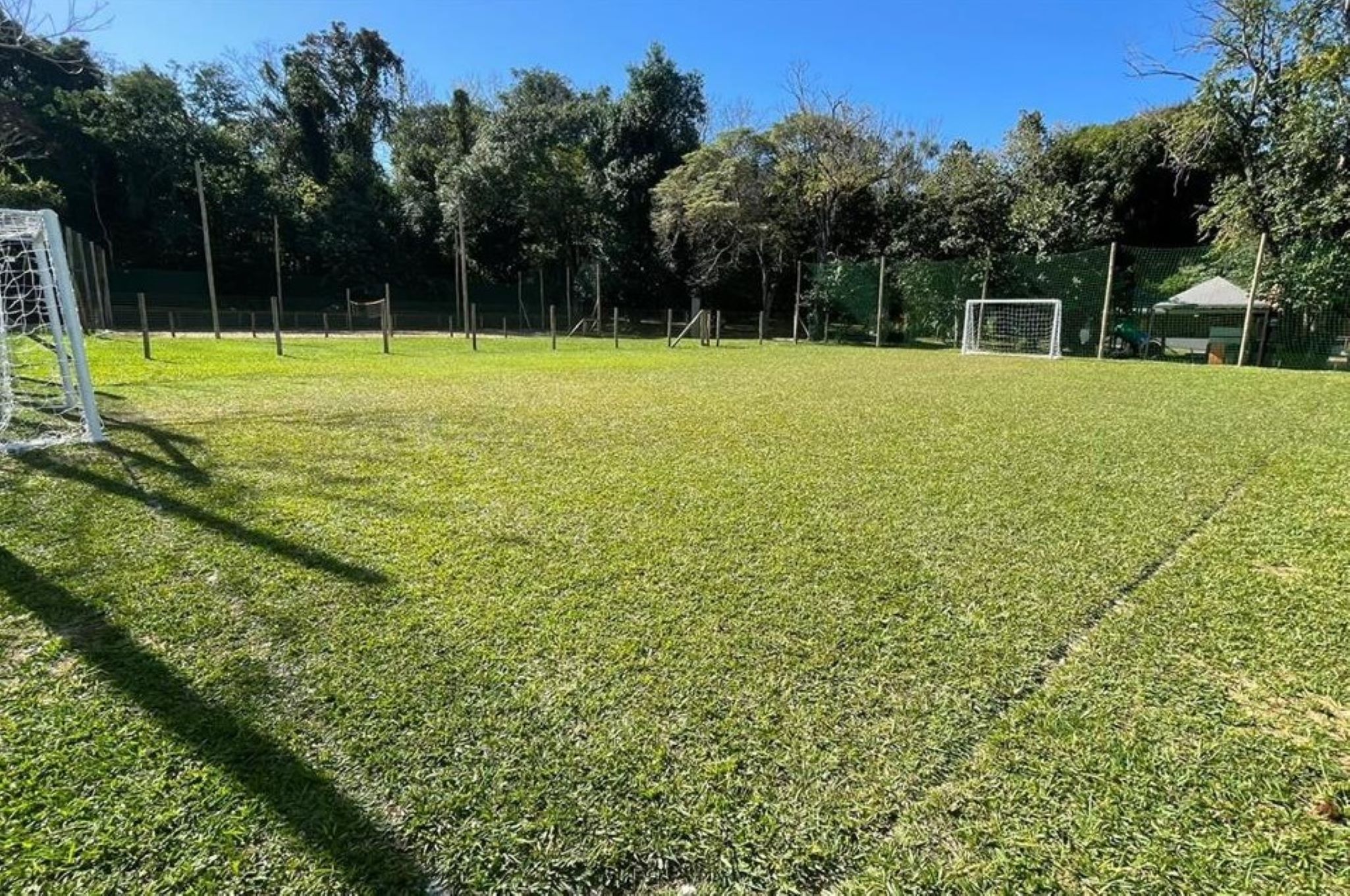 A grassy field with a goalpost and a fence.