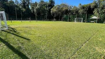 A grassy field with a goalpost and a fence.