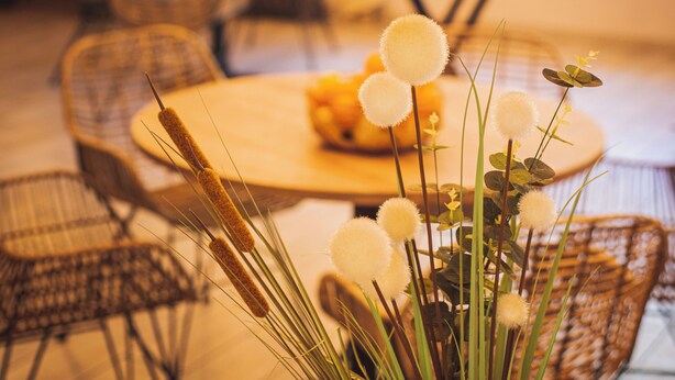 A dining area with a round table, wicker chairs, and hanging lights. - La Bastide des Golfs (Grasse)