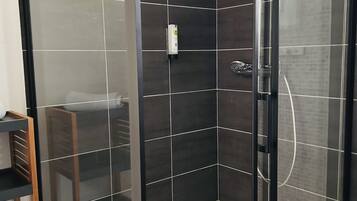 Un box de ducha moderno con baldosas oscuras y puerta de cristal.