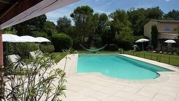 Una piscina al aire libre, sillones reclinables de piscina