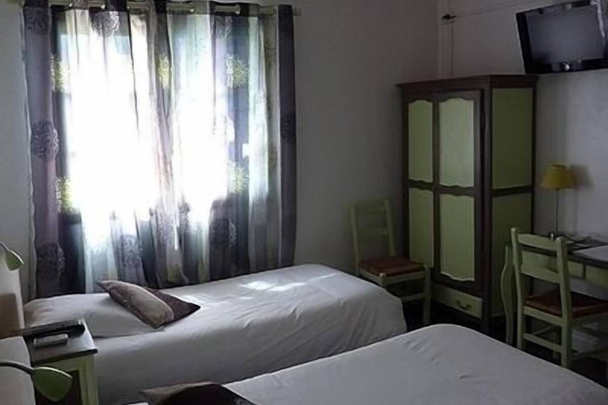 Una habitación con dos camas, televisión, escritorio y una silla.