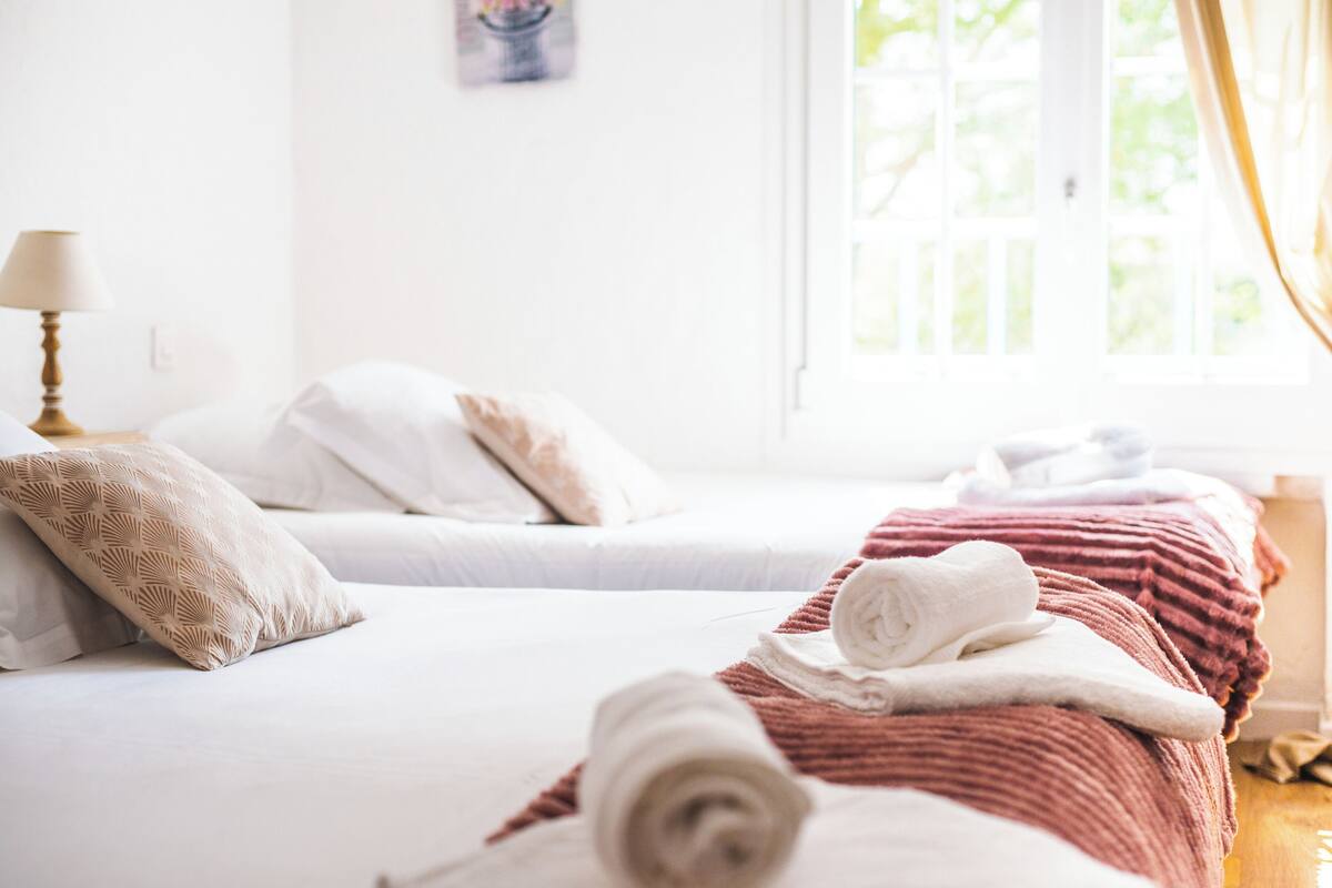 Una habitación de hotel con dos camas, una ventana con cortinas y una lámpara en la mesita de noche.