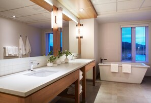 Une salle de bain moderne avec deux lavabos, un grand miroir et une baignoire.