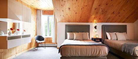 Ein Schlafzimmer mit zwei Betten, Holzboden, einem Einbauschrank und einem Fenster mit Blick auf Grünflächen.