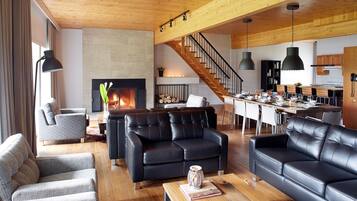 A modern living room with a fireplace, leather sofas, and a wooden dining area.