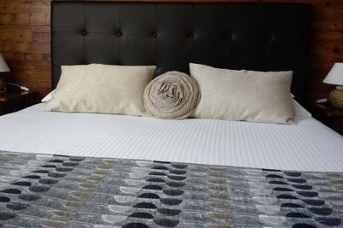 A bed with a black headboard, two pillows, and a rolled blanket.