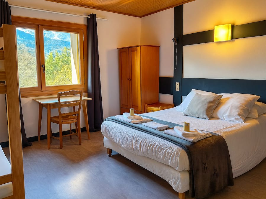 A bedroom with a bed, a desk, and a chair.