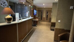 A reception area with a reception desk, a clock, a television, and a sign indicating the reception. - Hôtel de L'Ecu (Jonzac)