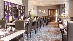 A modern dining area with tables set for service, a wine display, and a reception desk. - Hôtel de L'Ecu (Jonzac)