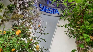 Entrada de un edificio con un letrero que dice "SIERRA" y abundante vegetación a su alrededor.