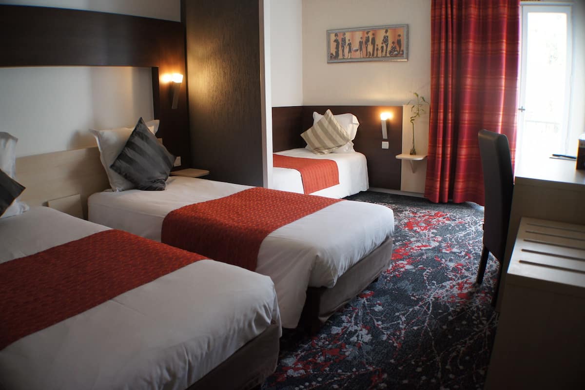 Una habitación de hotel con dos camas, un escritorio y una silla.