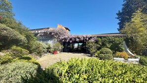 Un jardín con un edificio identificado como 'LA SIERRA', rodeado de abundante vegetación y plantas en flor.