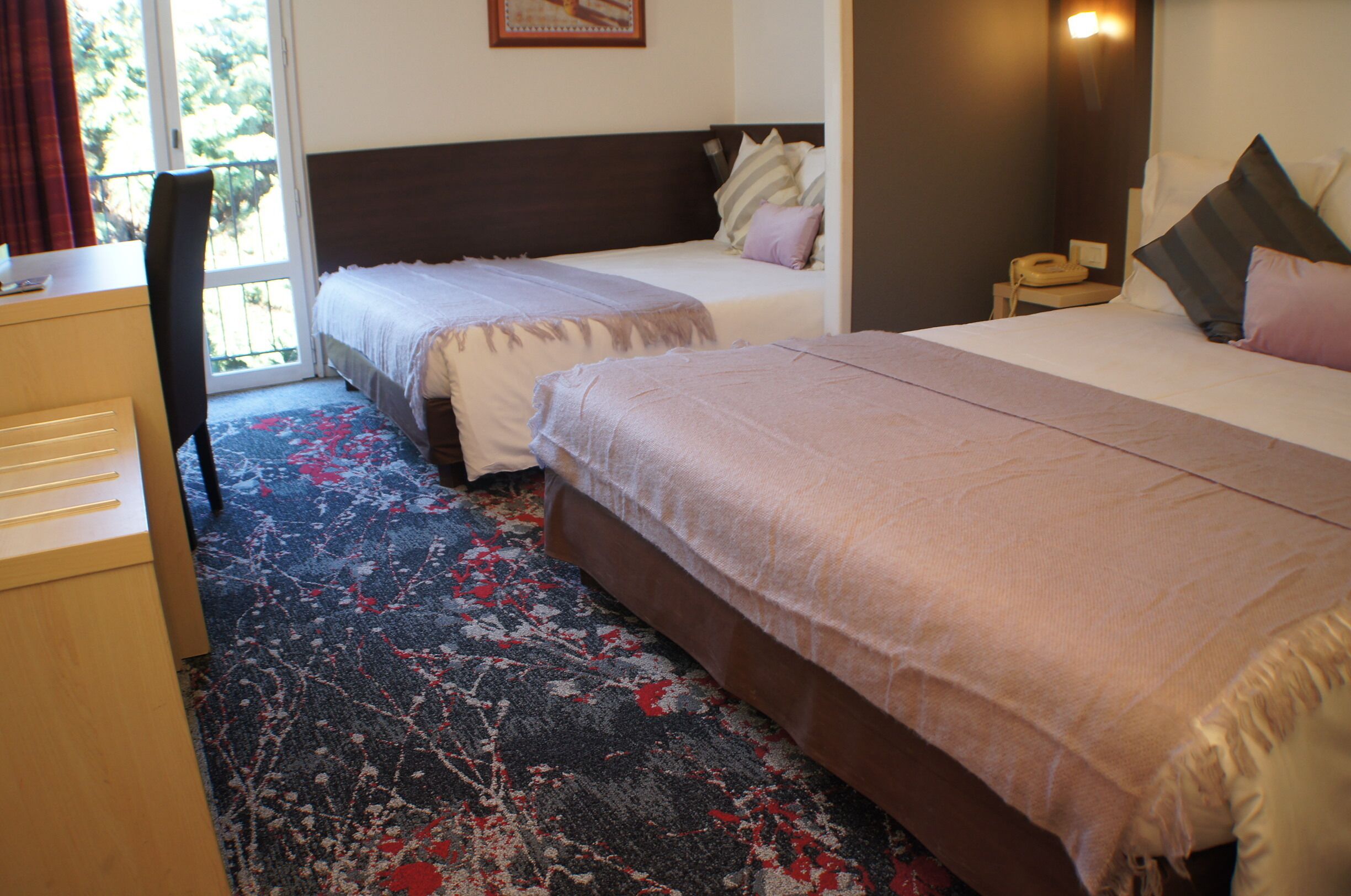 Une chambre d’hôtel avec deux lits, un bureau et une chaise.