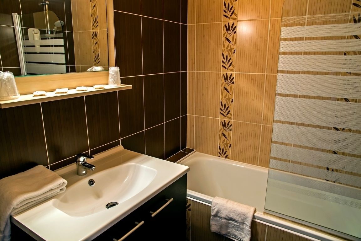 A modern bathroom with a sink, mirror, and bathtub.