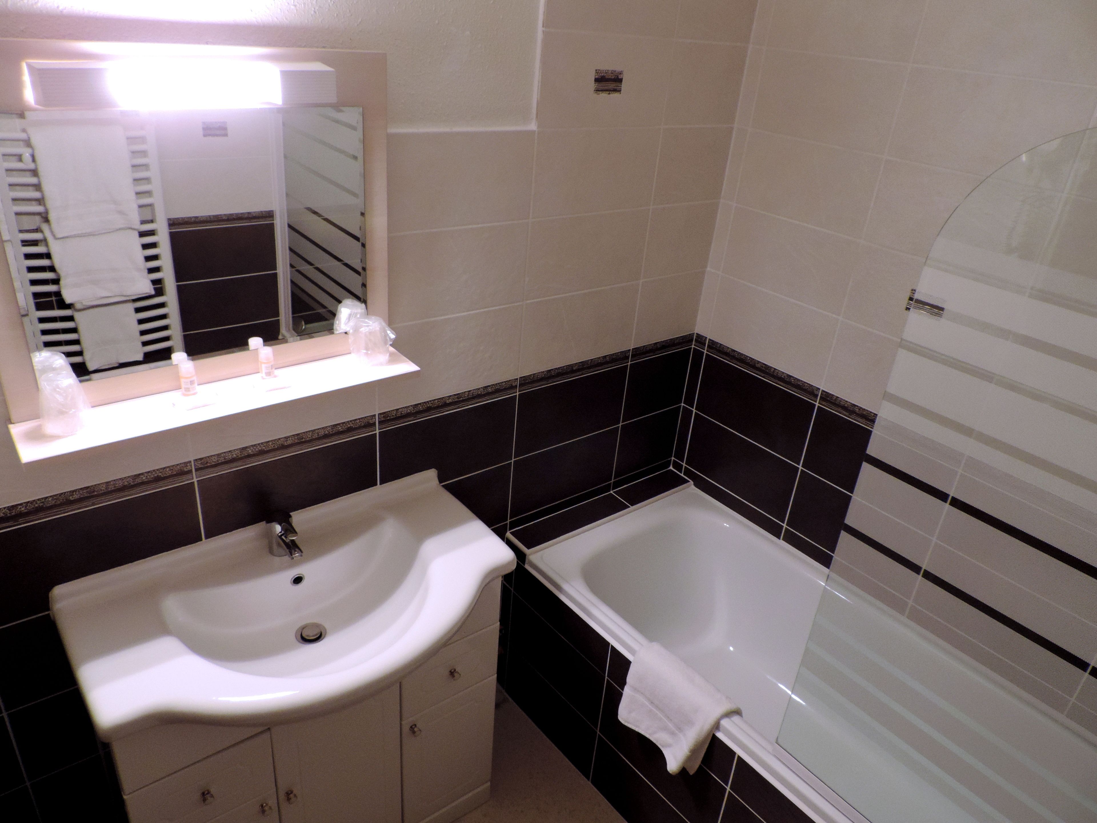 A bathroom with a white sink, a mirror, and a bathtub.