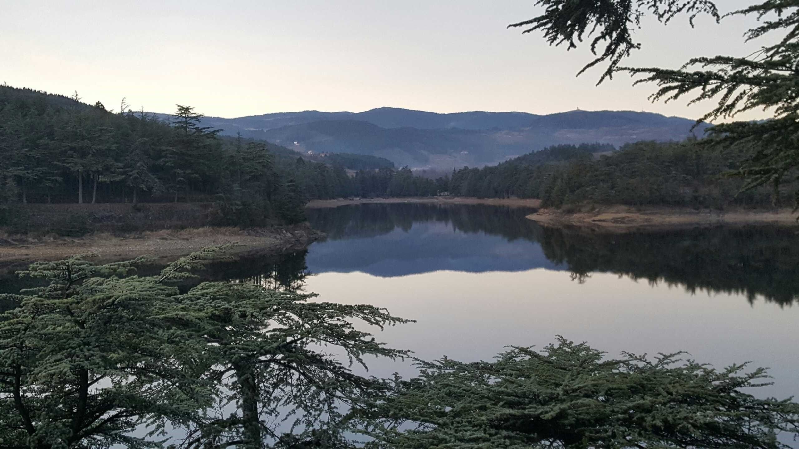 A serene lake surrounded by dense forest and hills.