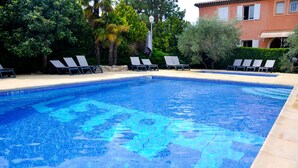 A swimming pool with clear blue water, surrounded by lounge chairs and greenery. - Hôtel Restaurant L'Etape (Bouc-Bel-Air)