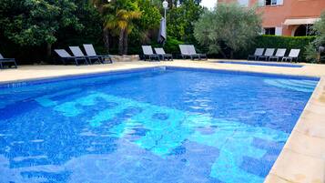 Una piscina al aire libre de temporada, sombrillas