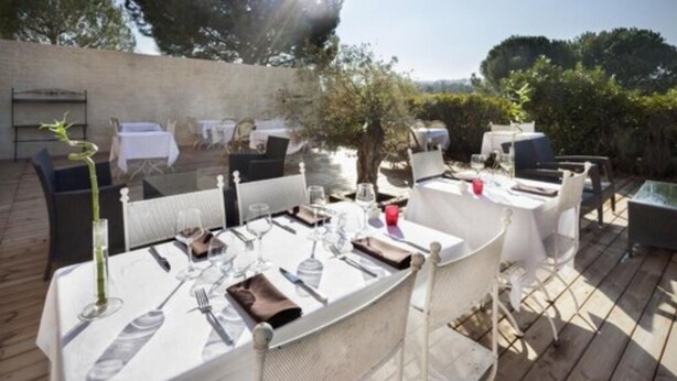 An outdoor dining area with tables set for a meal, surrounded by greenery and a clear sky. - Hôtel Restaurant L'Etape (Bouc-Bel-Air)