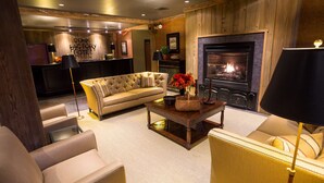 A cozy hotel lobby with a fireplace, sofas, and a reception desk.