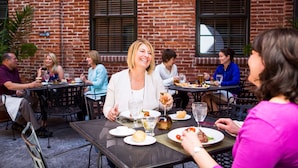 A group of people dining at an outdoor table with a brick wall in the background.