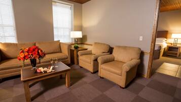 A room with a sofa, two armchairs, a coffee table with a vase of flowers, and a mirror.