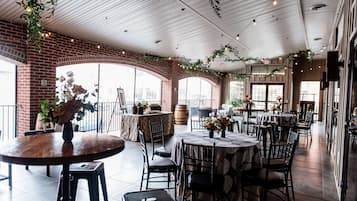 Un espace de restauration intérieur avec des murs en briques, de grandes fenêtres et des tables avec des chaises.