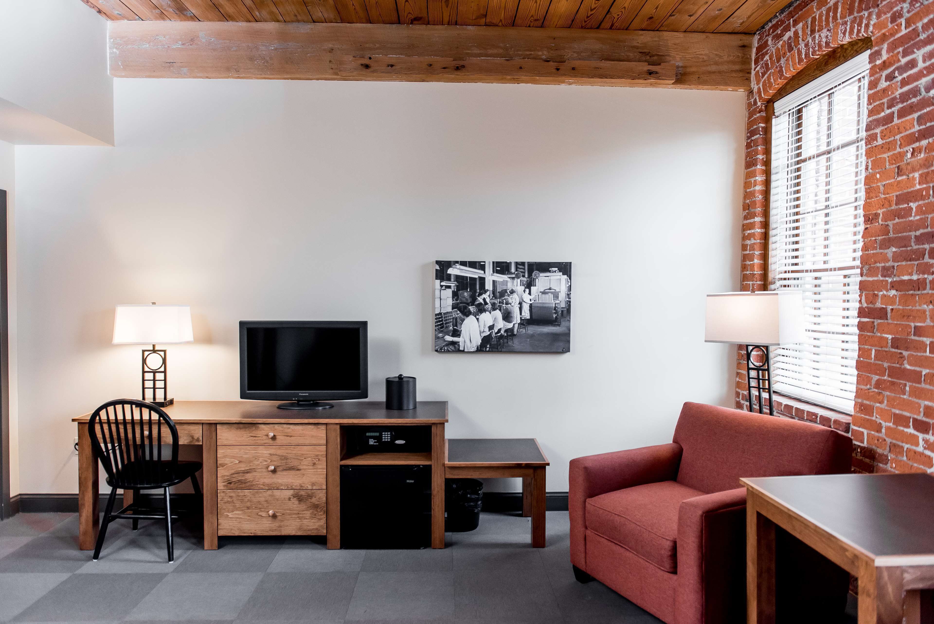 Una habitación con un escritorio de madera, un televisor, un sofá rojo y una silla negra.