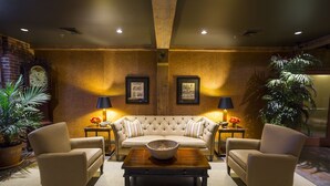 A cozy lounge area with a tufted sofa, two armchairs, a wooden coffee table, and two lamps.
