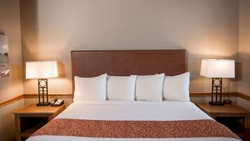 A hotel room with a large bed, two bedside tables, a nightstand, and a headboard.