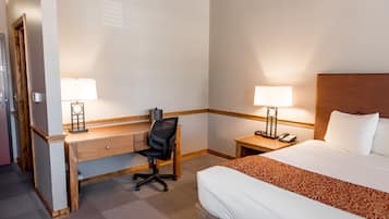 A hotel room with a bed, a desk, two lamps, and a telephone.