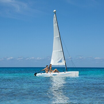 A sailboat with two people on the water.