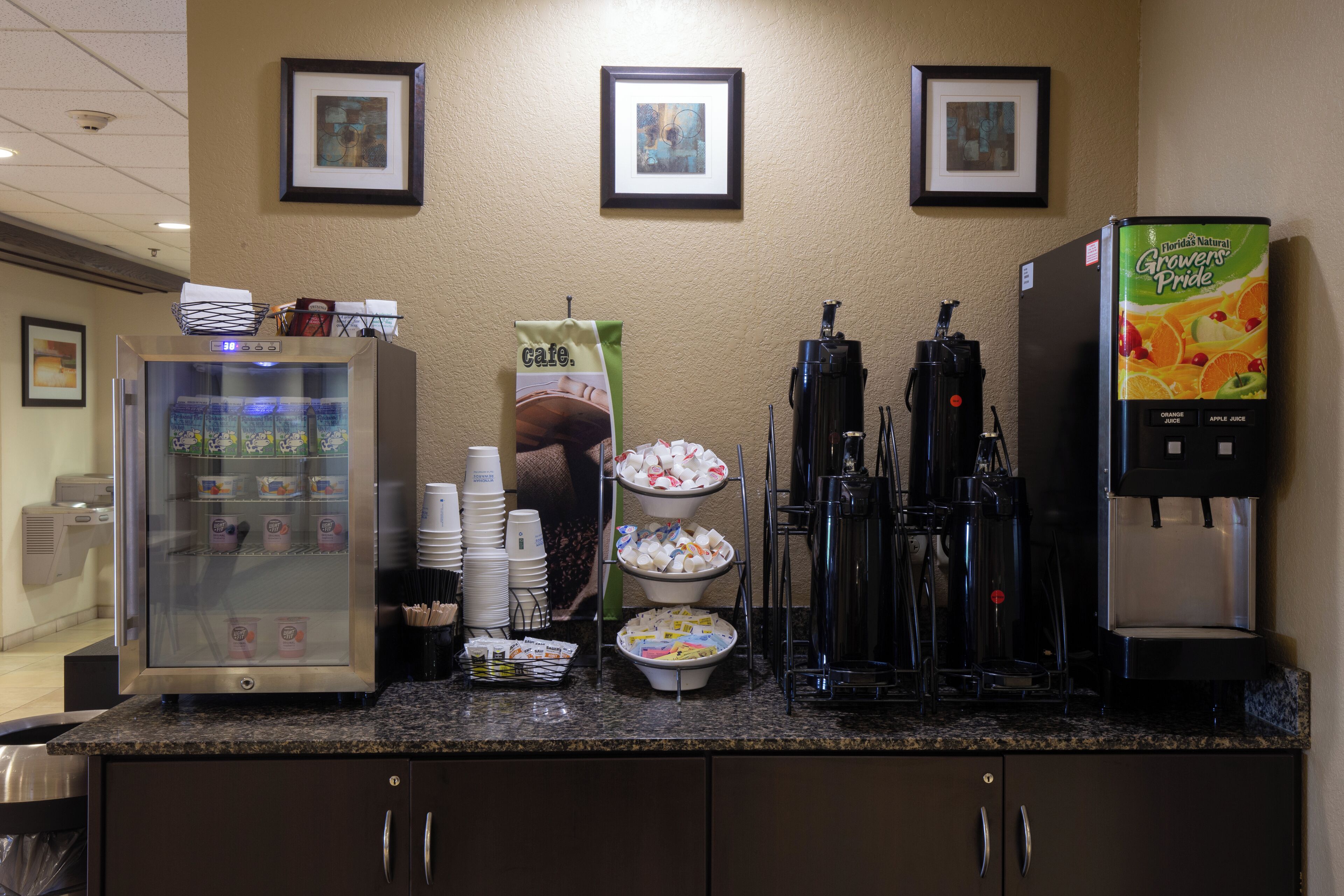 A breakfast bar with a coffee machine, a refrigerator, and a beverage dispenser.