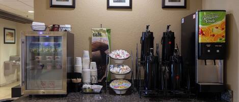 A breakfast bar with a coffee machine, a refrigerator, and a beverage dispenser.