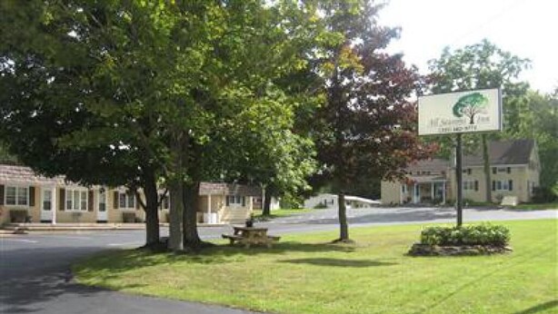 A street view with a sign for a hotel, a picnic table, and a grassy area with trees.