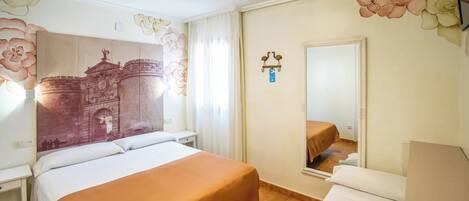 Una habitación de hotel con una cama grande, una mesita de noche, un armario, un espejo y una pared decorada con motivos florales y arquitectónicos.