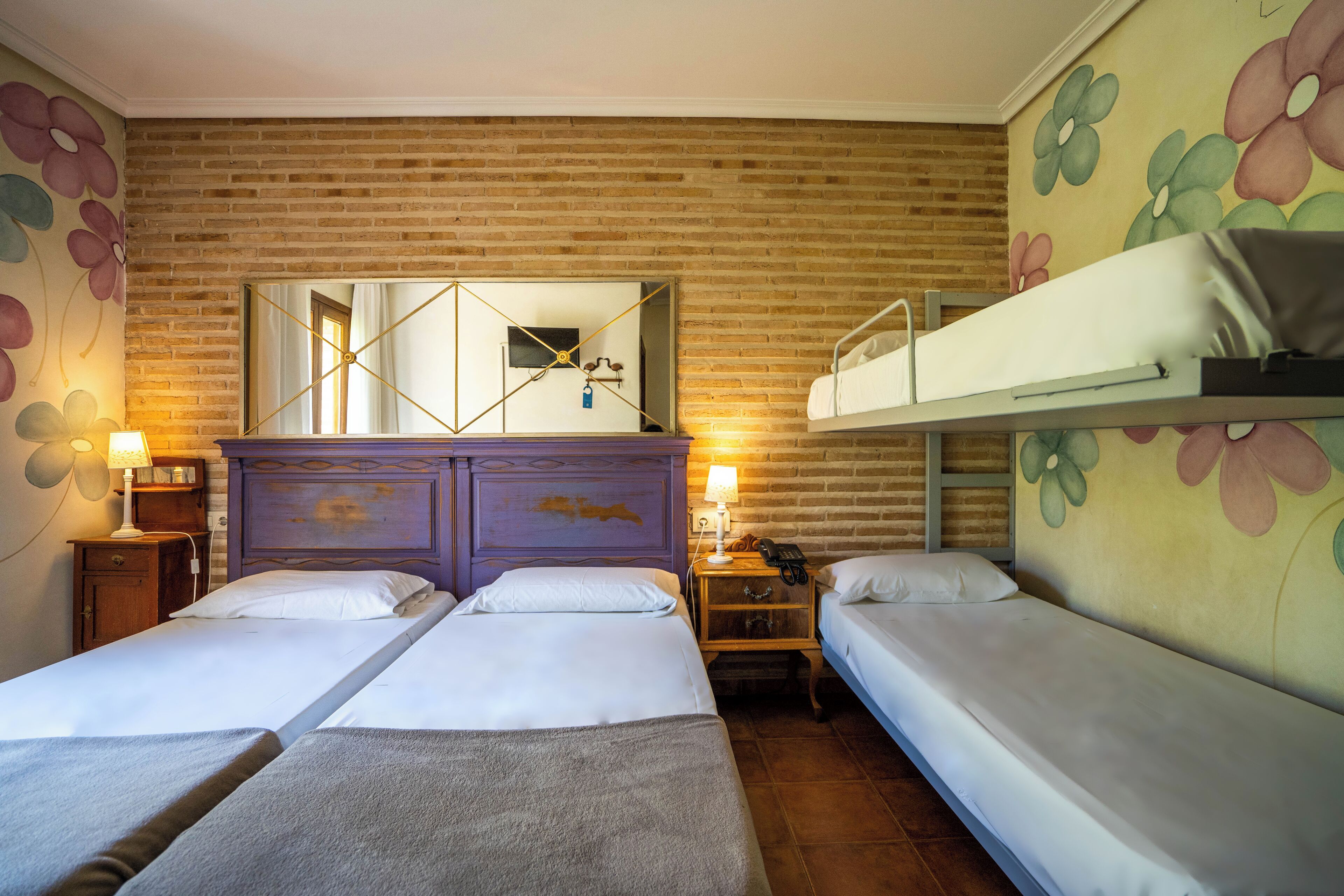 A hotel room with two single beds, a wooden headboard, a mirror, and a brick wall.