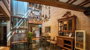 A spacious lobby with a glass floor, wooden furniture, and a brick wall. - YIT Puerta Bisagra (Toledo)