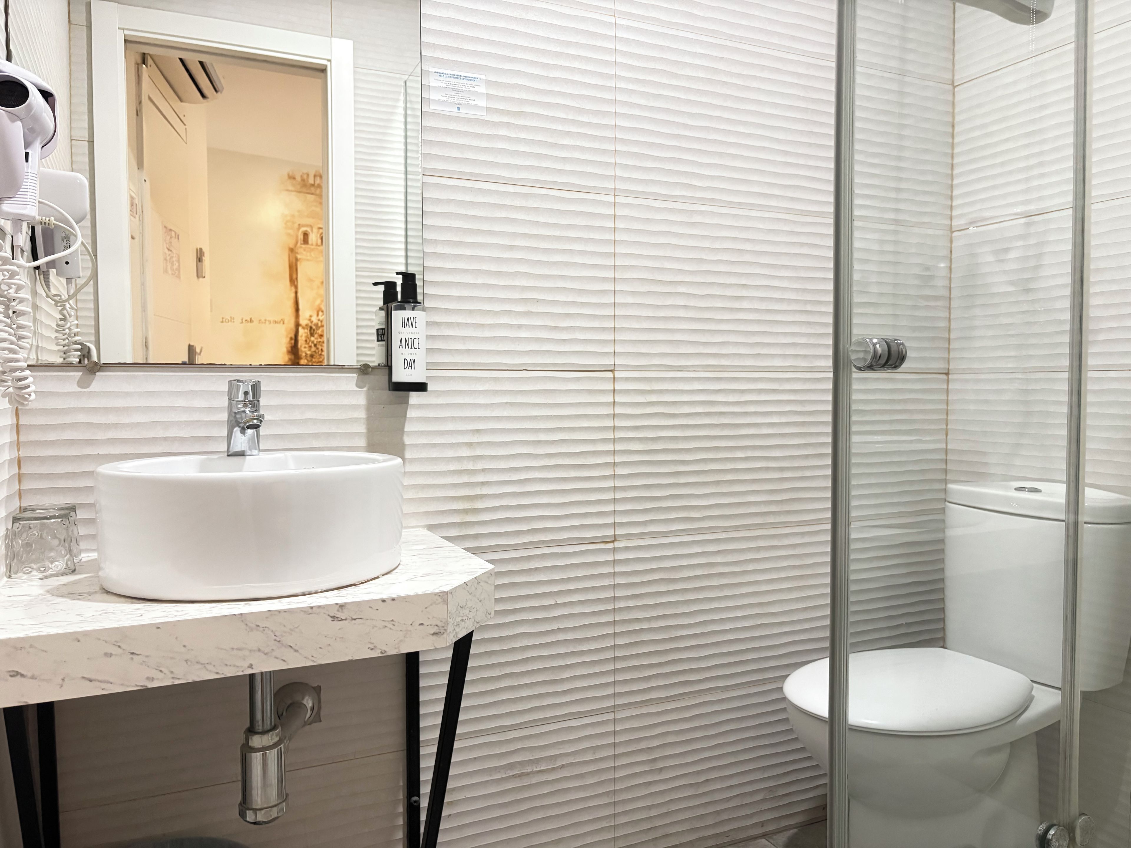 A bathroom with a white sink, a mirror, and a toilet.