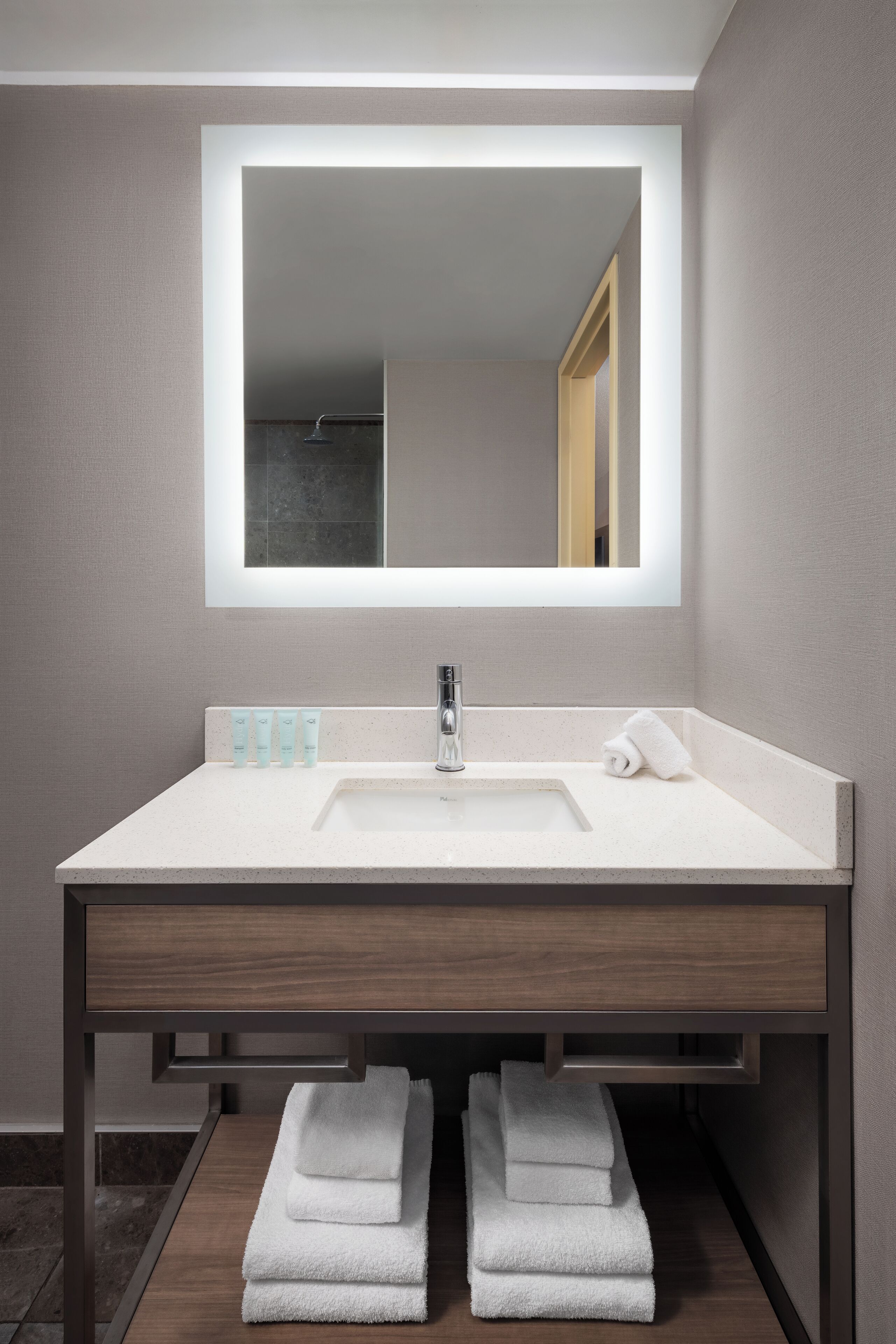 Une salle de bain moderne avec un grand miroir, un lavabo et un porte-serviettes.