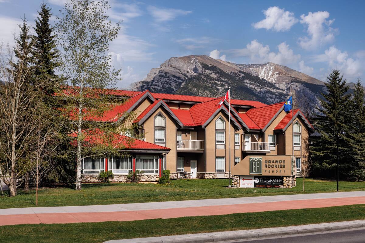 A hotel with a red roof, a signboard, and a mountain in the background.