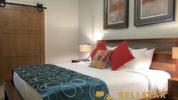 Une chambre d’hôtel avec un lit, une table de chevet, une lampe, une armoire en bois et deux tableaux encadrés au mur.
