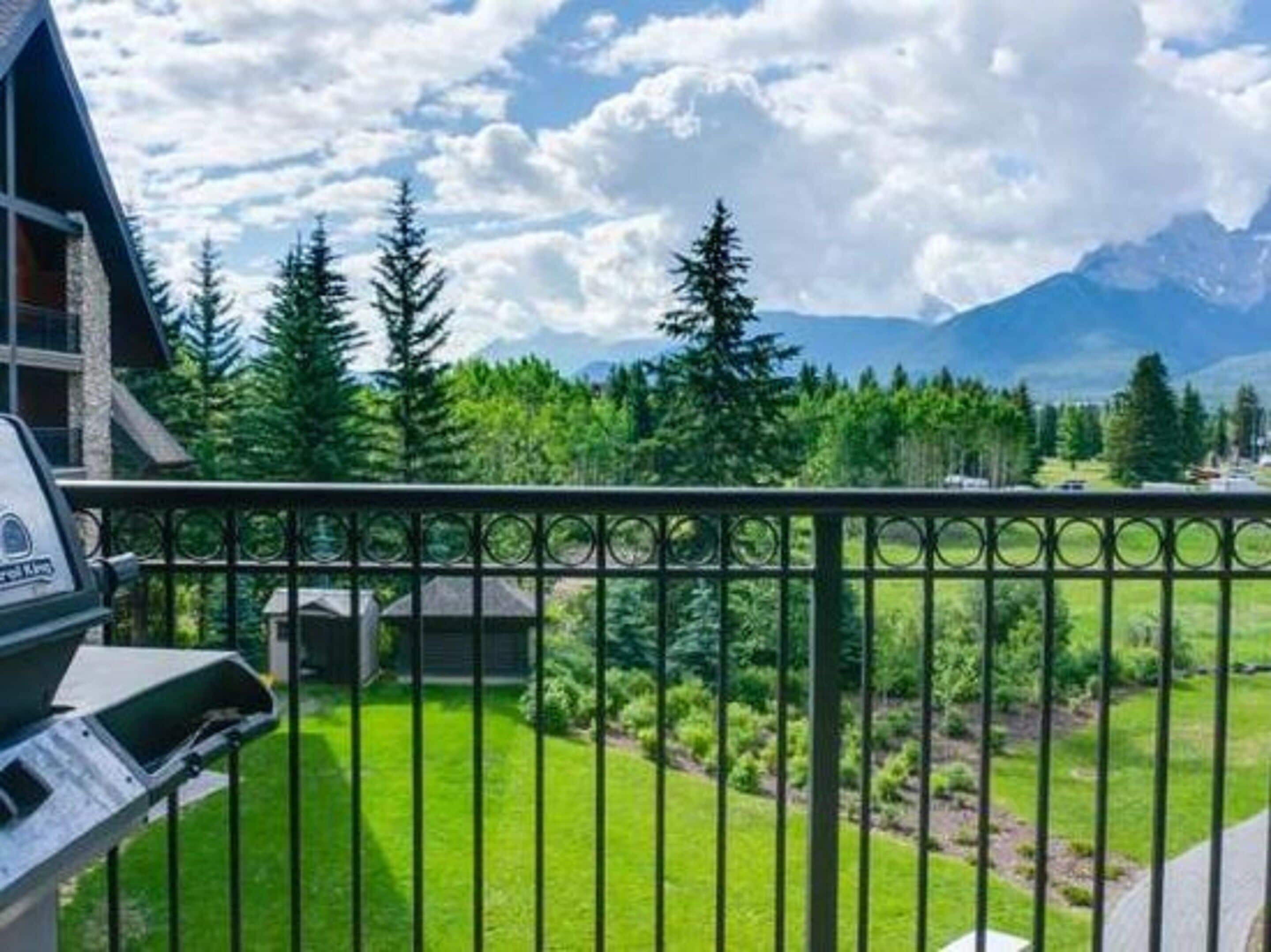 A mountain cabin with a balcony overlooking a lush green landscape and distant mountains.